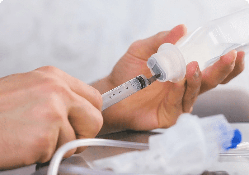 Syringe drawing liquid from a vial.