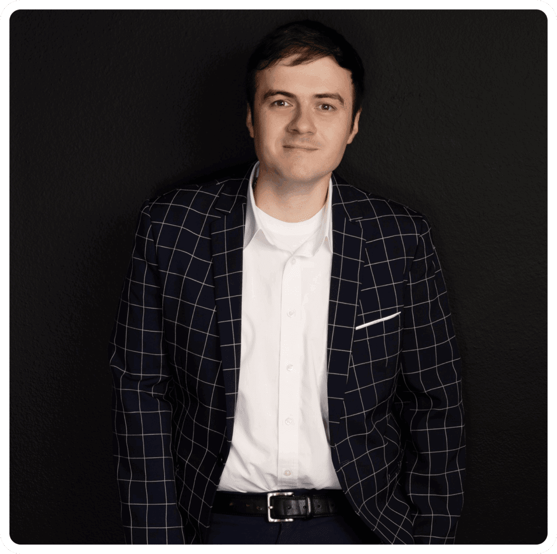 Man in checkered suit, standing against wall.